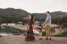 a man and woman holding hands while standing on top of a hill