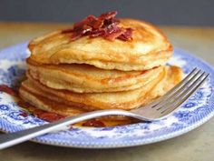 a stack of pancakes on a blue and white plate with a fork