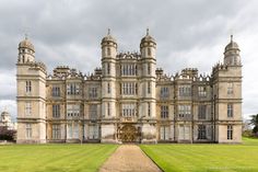 an old building with many windows on the front and side of it, surrounded by green grass