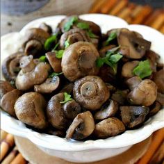 a white bowl filled with mushrooms on top of a table