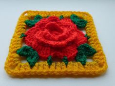 a crocheted square with a red rose on it