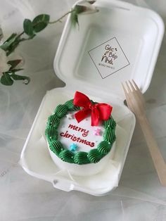 a cake in a box with a red bow on it and a fork next to it