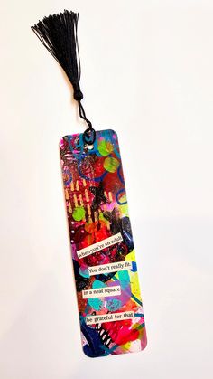 a bookmark hanging from a string on a white background with colorful designs and words