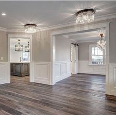 an empty living room with wood floors and chandeliers