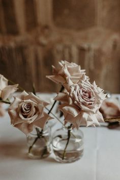 three glass vases with roses in them on a table