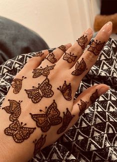 a woman's hand with hendi tattoos on it and butterflies drawn on the palm