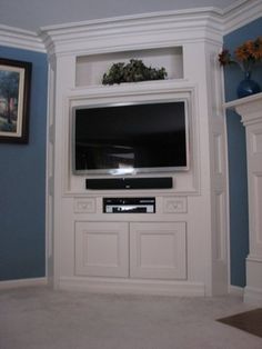 a flat screen tv sitting on top of a white entertainment center in a living room