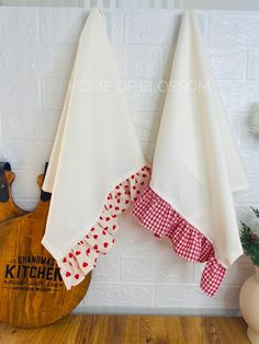 two white kitchen towels hanging on the wall next to a cutting board and knife holder