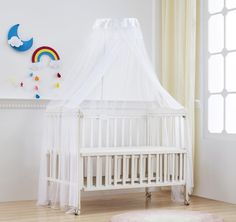 a baby crib with a white canopy and rainbow decorations on the wall behind it