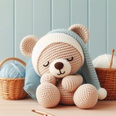 a crocheted teddy bear sitting on top of a table next to knitting supplies