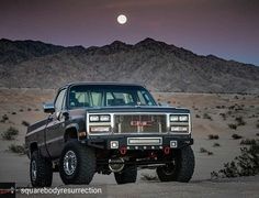 the truck is parked in the desert at night with the full moon visible behind it