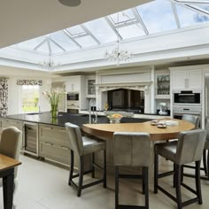 a large kitchen with an island table surrounded by chairs and counter tops in front of a skylight