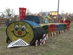 a train made out of hay sitting in the grass