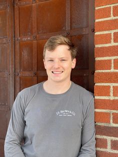 a young man standing in front of a brick wall with his hands on his hips