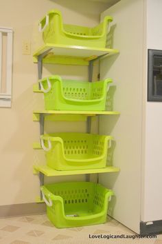 three green baskets are stacked on the wall next to a refrigerator in a kitchen area