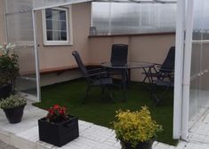 an enclosed patio area with chairs and tables in the grass next to potted plants