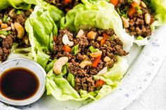 lettuce wraps filled with meat and vegetables on a plate next to dipping sauce