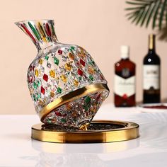 a decorative glass vase sitting on top of a table next to bottles and a bottle opener