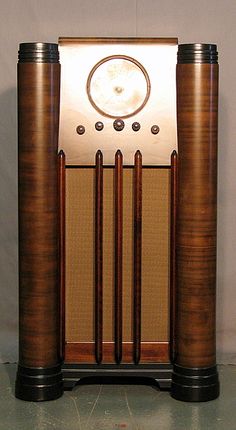 an old fashioned radio sitting on top of a wooden stand in front of a white wall