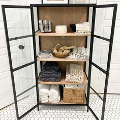 an open shelving unit with baskets and towels