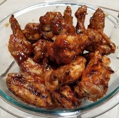 a glass bowl filled with chicken wings on top of a table