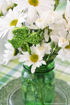 white daisies and green broccoli in a mason jar on a checkered tablecloth