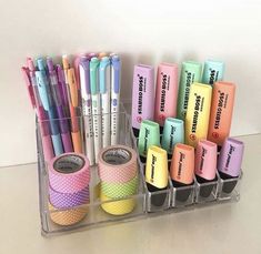 several different colored pens and pencils are in a holder on the table next to each other