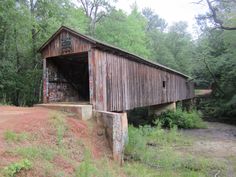 an old covered bridge with graffiti on it's side and trees in the background