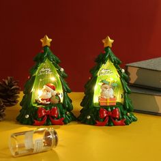 two small christmas trees sitting on top of a table next to a bottle of wine