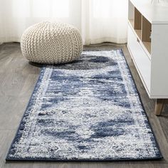 a blue and white area rug on the floor in front of a window with curtains