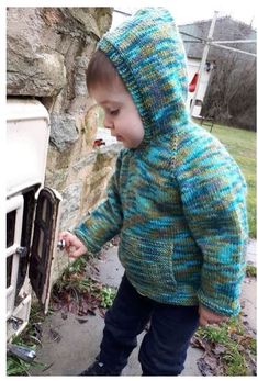 a little boy that is standing in front of an oven and looking at something on the ground