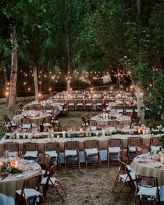 an outdoor wedding reception set up in the woods with lights strung over tables and chairs