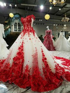 a red and white wedding dress on display in a store window with roses all over it