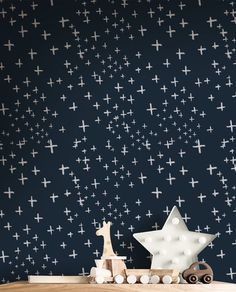 a wooden table topped with a toy horse next to a wall covered in white crosses