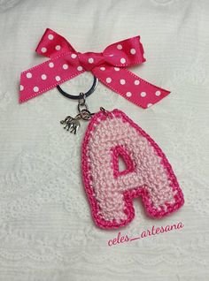 a pink and white keychain with a polka dot bow on it's side