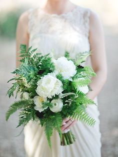 a bride holding a bouquet of white and green flowers