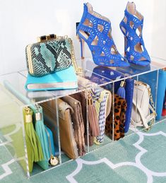 a clear shelf with shoes and purses in it on a blue carpeted floor