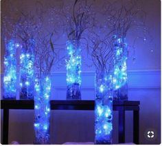 three vases filled with blue lights on top of a table