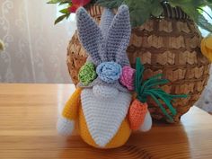 a crocheted stuffed animal sitting on top of a table next to a potted plant