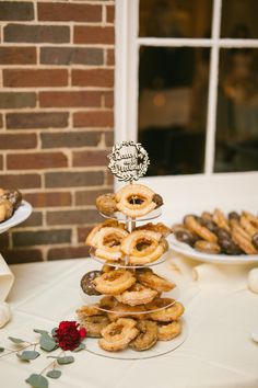 a table topped with lots of donuts on top of plates next to a brick wall