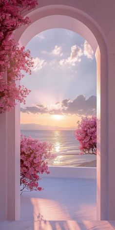 an archway leading to the beach with pink trees and water in the background at sunset