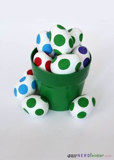 a green bowl filled with white and red polka dot balls on top of a table