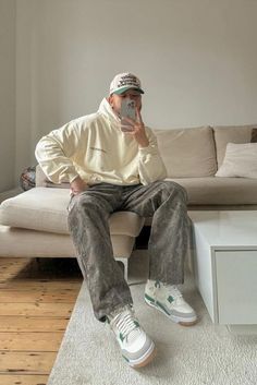 a man sitting on top of a couch while holding a cell phone to his face