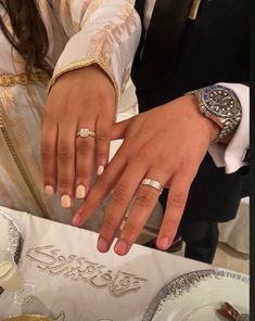 two people standing next to each other with wedding rings on their hands and one holding the other's hand