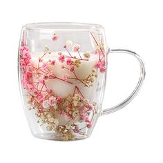 a glass cup filled with flowers and two white candles on top of the inside of it