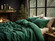 a bed with green sheets and pillows next to a fire place in front of a window