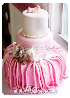 a three tiered cake with pink and white icing