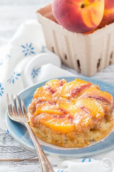 a blue plate topped with food next to a bowl of peaches and a fork