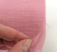 someone is removing the fabric off of their pink shirt with gold flecks on it