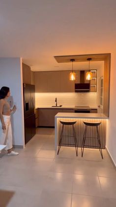 a woman standing next to a kitchen counter in a room with white tile flooring